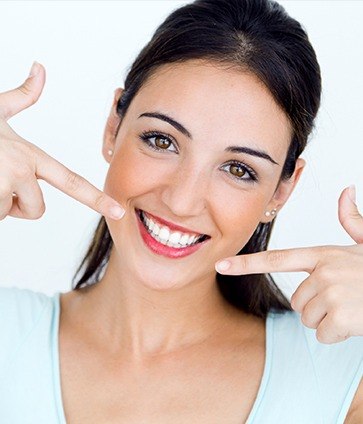 Woman pointing at flawless smile after cosmetic dentistry