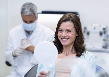 smiling dental patient holding a hand mirror