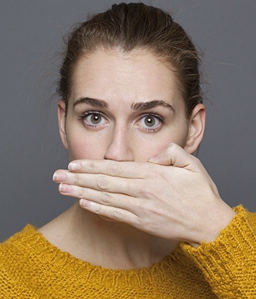 Woman covering her mouth before periodontal therapy