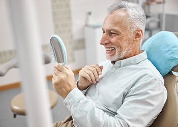 Man with dental implants in North Dallas using a dental mirror
