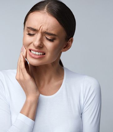 Woman in pain holding cheek before emergency dentistry in North Dallas