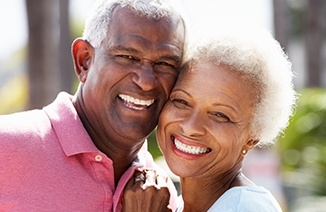 Older man and woman outdoors with healthy smiles after periodontal therapy