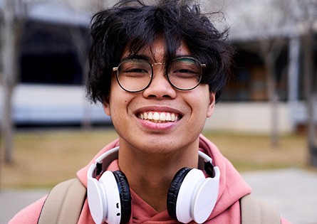 Closeup of teenage boy with black glasses smiling