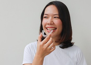 Teen girl smiling while holding clear aligner