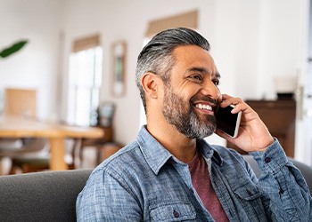 Man smiling while talking on phone at home