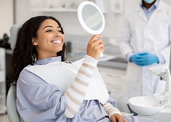 Woman smiling at reflection in handheld mirror