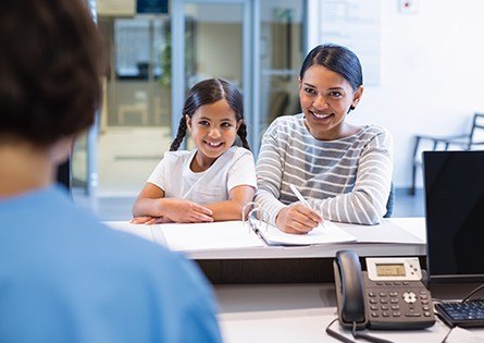 Mother and daughter checking in at dental office reception desk