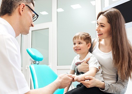 Mother holding infant child in dental chair