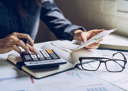 Woman using a calculator at her desk and holding an envelope 