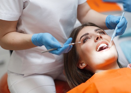 A young woman having her teeth checked by a dental hygienist during a visit