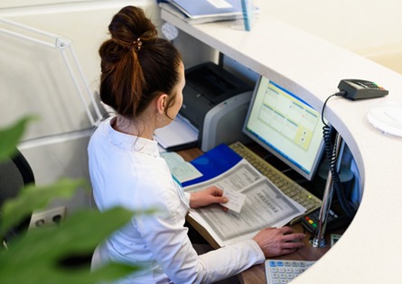 A woman behind a reception desk checking dental insurance coverage