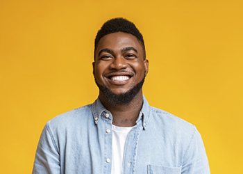 man smiling in front of a yellow background