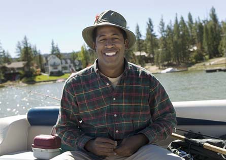 a smiling person fishing on a lake