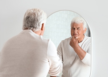 Denture patient in Dallas looking at themselves in the mirror