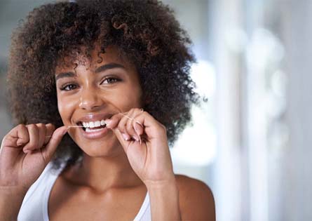 woman flossing to prevent dental emergencies in North Dallas