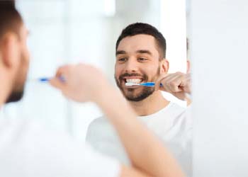 man brushing his teeth in front of a mirror