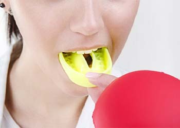 person putting a yellow mouthguard over their teeth