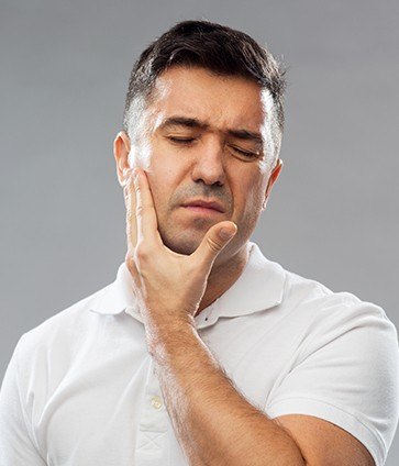 Man holding jaw in pain before tooth extraction