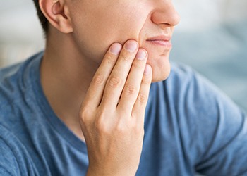 Man rubbing jaw after getting dental implants in North Dallas