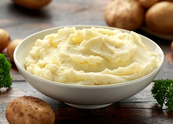Bowel of mashed potatoes surrounded by whole potatoes