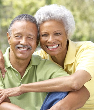 An older couple with implant supported dentures hugging and smiling