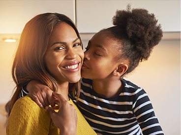 Young girl giving her mother a kiss on the cheek