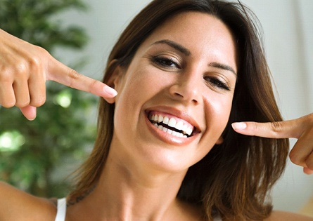 Smiling woman pointing to her straight teeth