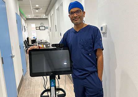 Doctor Patel standing in a hallway with a monitor on wheels