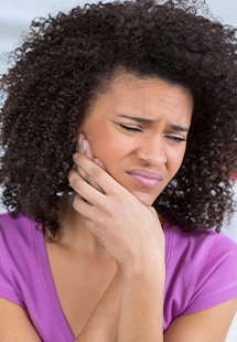 woman holding her cheek in pain