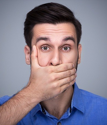 Man covering his mouth before replacing missing teeth