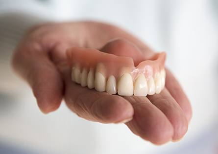 Hand holding full denture