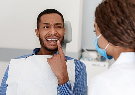 Man at dental office pointing to his tooth in pain