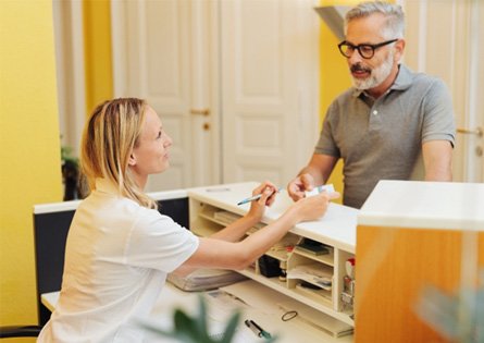 patient talking to staff member at front desk   