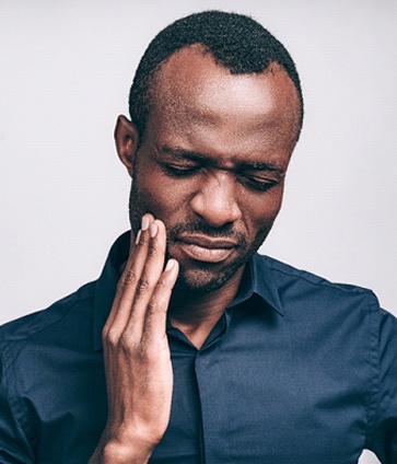 person holding their mouth in pain before root canal therapy