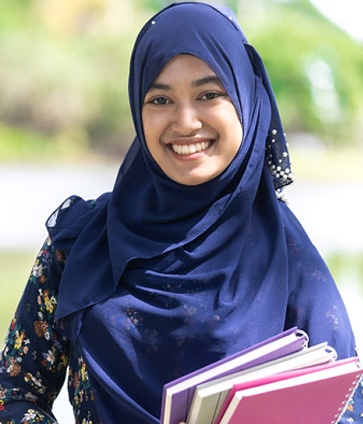 student holding books and smiling after root canal treatment