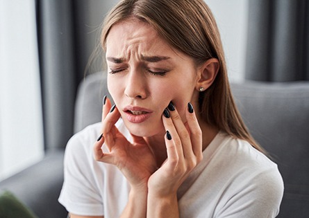 woman holding her face in pain and needing root canal treatment