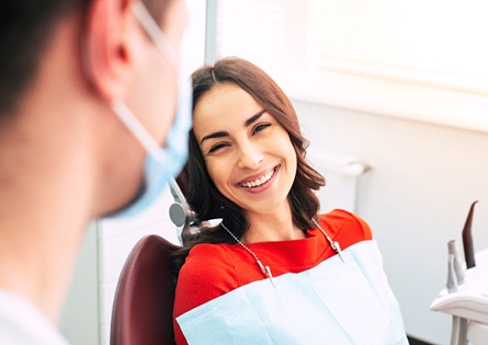 Woman smiling at dentist during teeth whitening appointment