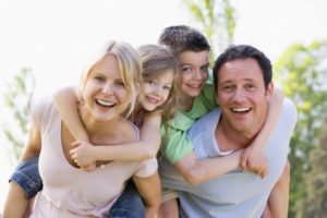 Parents and kids smiling together after visiting family dentist