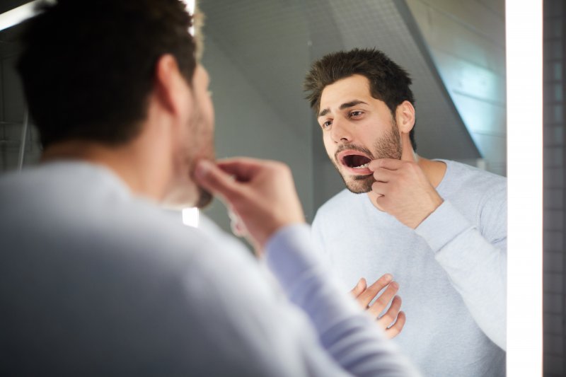 a man looking at his teeth in the mirror