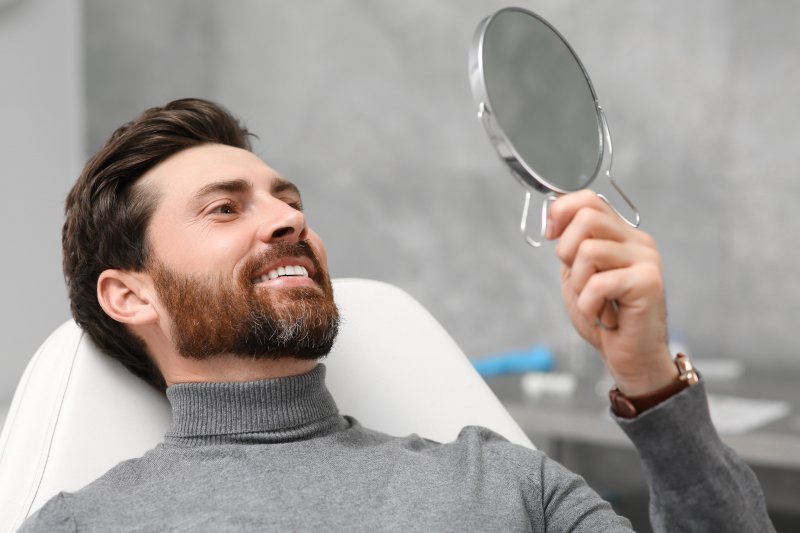 Man looking at his smile after dental implant surgery