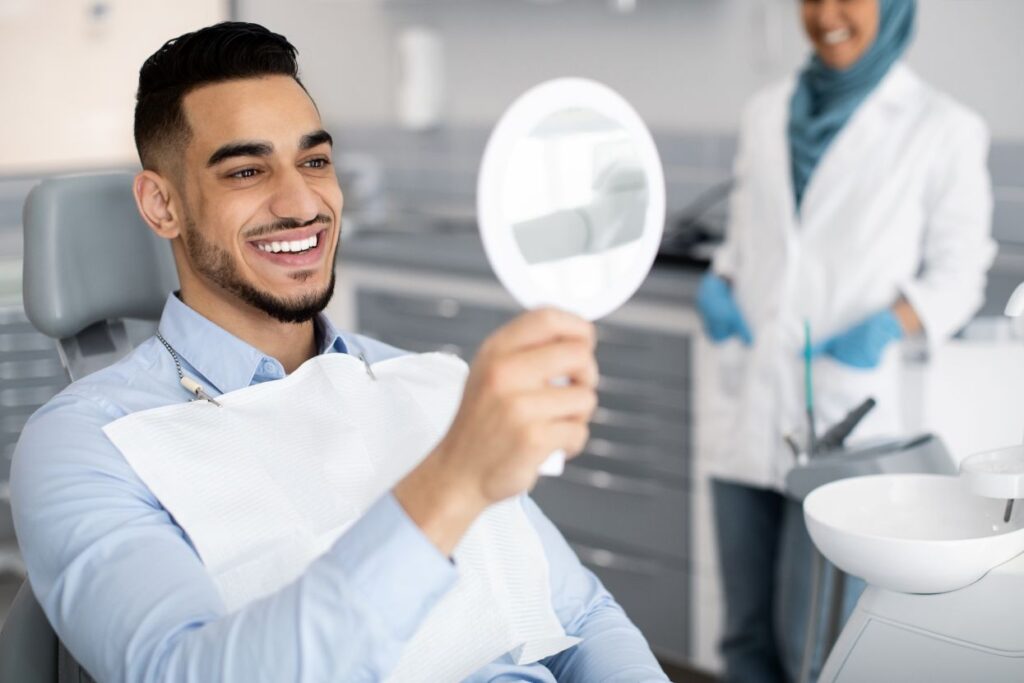 A man looking at his new veneers in a mirror